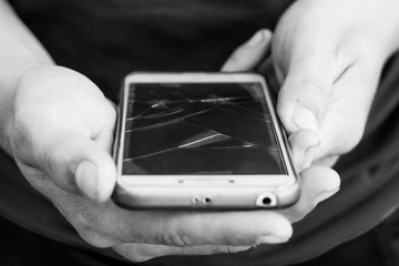 The guy holds the phone with a broken display. Cracks on the phone glass_