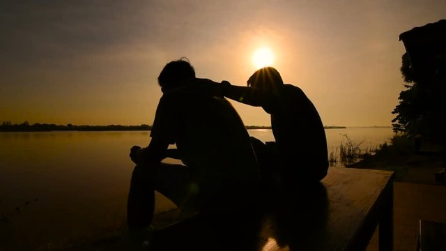 Silhouette of Two friends sitting near the river.