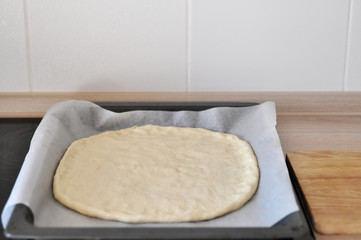 Cooking pizza dough at home in the kitchen. Closeup