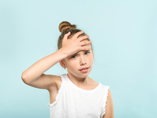 Fototapeta premium facepalm embarrassment and shame emotion. ashamed girl covering her forehead with a hand. young cute child portrait on blue background.