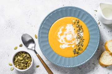Pumpkin cream soup on light stone table.