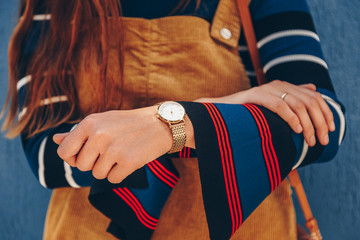 close up, young fashion blogger wearing a corduroy dress and a white and golden analog wrist watch....