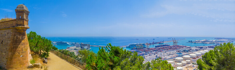 Beautiful panoramic view of the sea, the sea port, the tower of the Fortress on Montjuic mountain in Barcelona (panorama of the South-Western part of the city – industrial area)