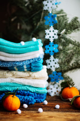 Knitted things. Sweaters are lying on a wooden table. Candles. Autumn. Cozy.