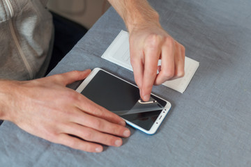 Smart solution technology concept. High angle top side profile view cropped photo replacement of protective film with a new one. Man carefully removes old protective glass from the smartphone screen