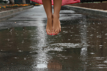close-up of a girl's feet dancing in a puddle after a summer rain - obrazy, fototapety, plakaty