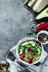 Salad with rocket salad, avocado, grapefruit, parmigiano, olive oil on a grey background, top view copy space