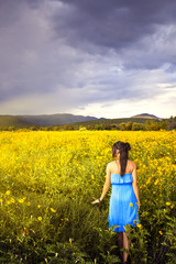 Fototapeta premium A woman walking through a beautiful field of wildflowers at sunset