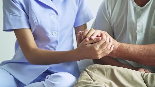 Comforting hand. Young nurse holding old man's hand. Senior care, care taker and senior retirement home service concept. Close up shot.