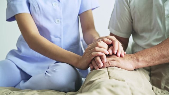 Comforting hand. Young nurse holding old man's hand. Senior care, care taker and senior retirement home service concept. Close up shot.