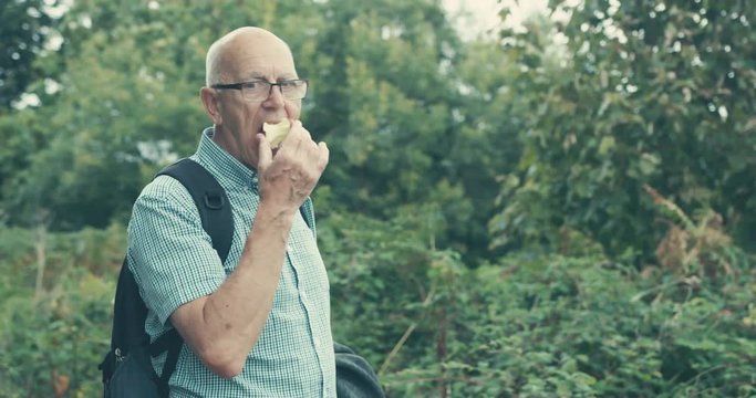 Senior man eating apple in nature