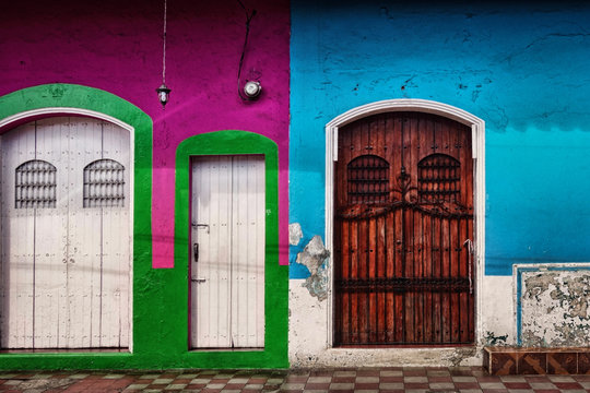 Three side-by-side colorful painted doorways with flaking paint and worn finish in the Colonial city of Leon in northern Nicaragua