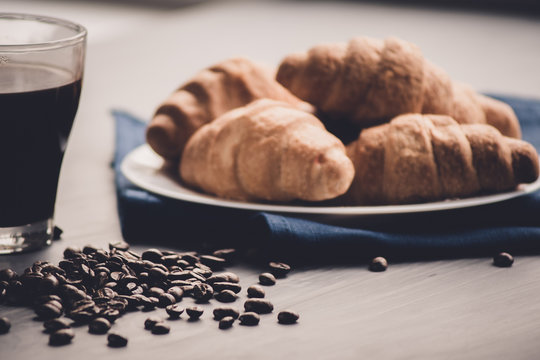 Top View. Macro Shot Of Fresh Croissants And Coffee On A Black Background. Mate Moody Color. Concept Of Breakfast. Dessert And Coffee Beans.