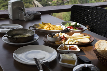 The enjoying breakfast at the cafe with friends. tomato,cheese ,omelette , olive ,jam ,bread in the wooden table at the beautiful view in Istanbul.