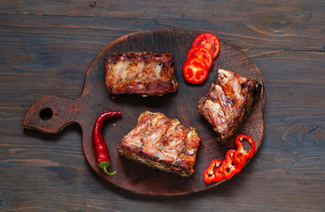Spicy hot grilled spare ribs from BBQ served with  hot chili pepper and lime on dark wooden background.  Banner.  Top view,  copy space, flat lay.