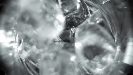 Macro shot of ice cubes falling into a cocktail glass and rolling around. Making of cocktail. - Powered by Adobe