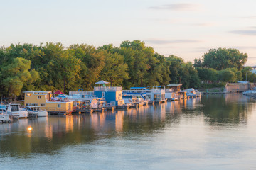 Naklejka premium Twilight image of Mississippi River from Raspberry Island. sunset with house boats, tree lined smooth river scene