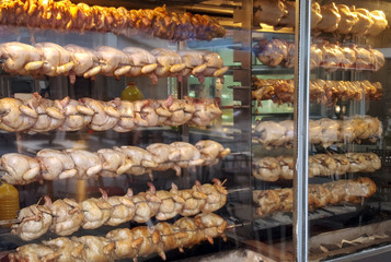 Roasted chickens in a row in a shop roaster