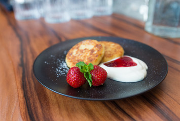 Cottage cheese pancakes. Russian syrniki with cranberry jam and yogurt, selective focus.