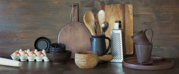 Crockery, clayware, dark utensils and other different stuff on wooden tabletop. Kitchen still life...