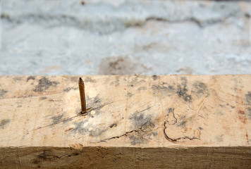 Close up a rusty nail pierce the logs. Dangerous of wood nail on the timber. harmful of construction site from material. Sources of tetanus germs concept.
