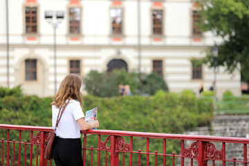 Młoda dziewczyna z katalogiem turystycznym na moście we Wrocławiu.
