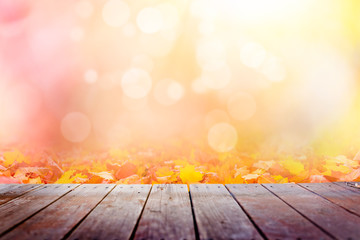 Multi colored autumn leaves bokeh background over wooden deck