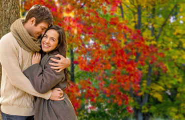 Fototapeta premium love, relationship and season concept - smiling couple hugging over autumn park background