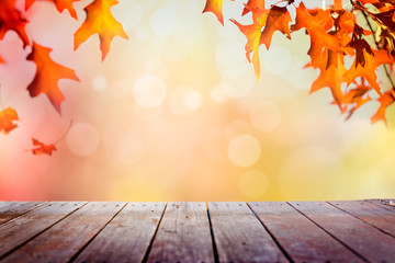 Naklejka na ściany i meble Multi colored autumn leaves bokeh background over wooden deck