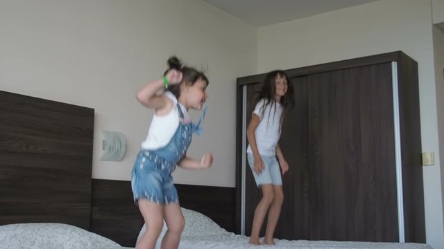 Children are jumping on the bed. Happy sisters jump on the beds in the bedroom.