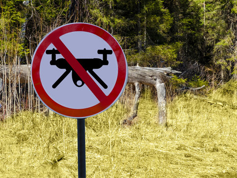 sign ban drones in the background of a Park or forest.