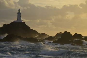 Cercles muraux Phare La Corbiere lighthouse, Jersey, U.K.  A storm from the Atlantic lands at of coastal landmark in Autumn.