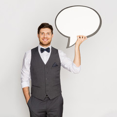 fashion, style and communication concept - happy man in suit holding blank text bubble banner