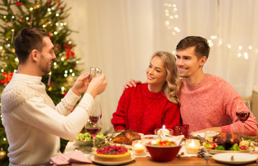 holidays and celebration concept - happy man photographing his friends at christmas dinner