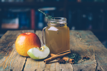 Apple cider (mulled cider) with cinnamon sticks and fresh apples on wooden background. Autumn drinks. Winter mood. Copy space.