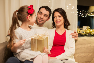 holidays, family and celebration concept - happy mother, father and little daughter with christmas present at home