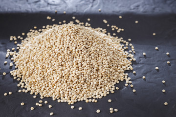 Fototapeta na wymiar Quinoa grains with spoon and bowl on black background