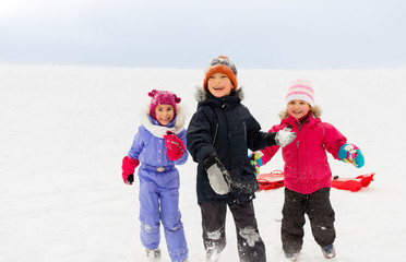 childhood, leisure and season concept - group of happy little kids in winter clothes playing outdoors