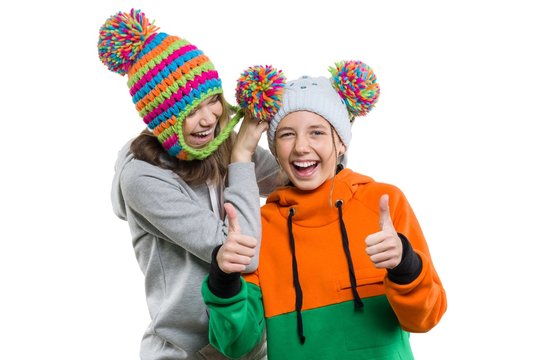 Winter portrait of two happy smiling pretty girls in knitted hats having fun, isolated on white background, people, youth and friendship concept