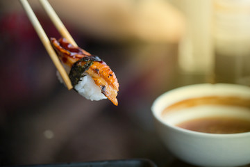 Close up chopsticks hold on sushi freshwater eel grilled. Japanese food for healthy. unagi sushi, premium sushi menu. image for background,wallpaper, copy space and menu list.