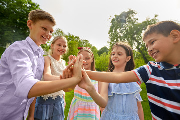 summer holidays, friendship, childhood, leisure and people concept - group of happy pre-teen kids making high five gesture in park