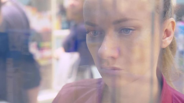 A woman looking at a glass display case in the store. 4k, background blur.