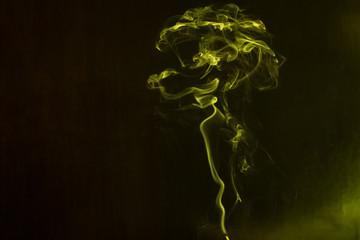 Yellow smoke forming random shapes against dark background