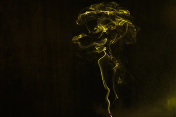 Yellow smoke forming random shapes against dark background
