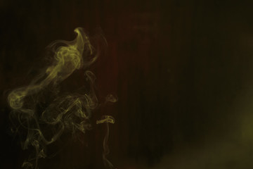 Yellow smoke forming random shapes against dark background