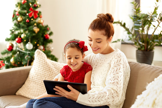 Christmas, Technology And Family Concept - Happy Mother And Little Daughter With Tablet Pc Computer At Home