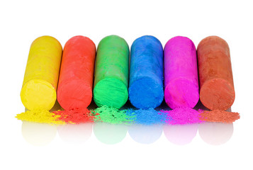 Closeup of multicolor chalk isolated on white background with shadow reflection. Chalks in variety of colors arranged on white underlay. Colorful chalk pastels on white backdrop. Multicolored Crayons
