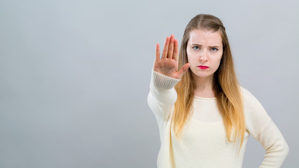 Young woman making a rejection pose on a gray background