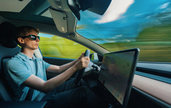 Man Driving A Luxury Vehicle Down The Road With Motion Blur