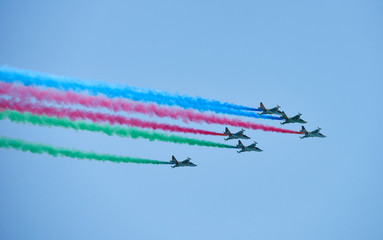 Modern military jet fighter airplanes flying in blue sky. Fighter jets fly together with colorful smoke